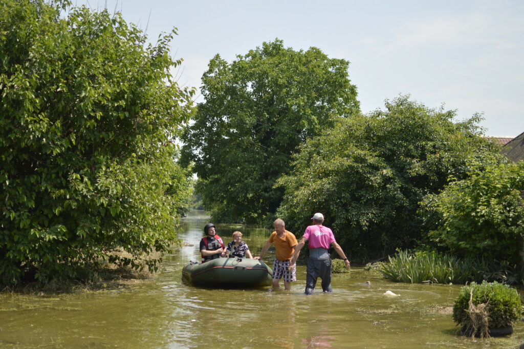 Hjelpearbeider fra Caritas i en gummibåt sammen med flomrammede i Kherson