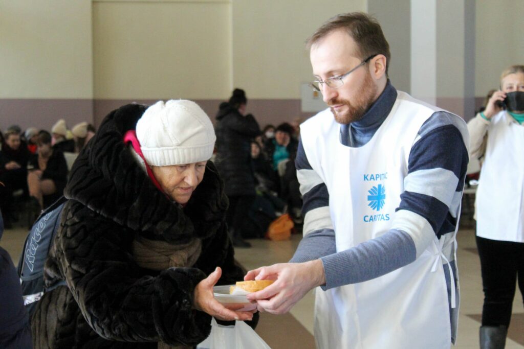 Eldre dame får utdelt brødskiver av en frivillig i Caritas Ukraina. 