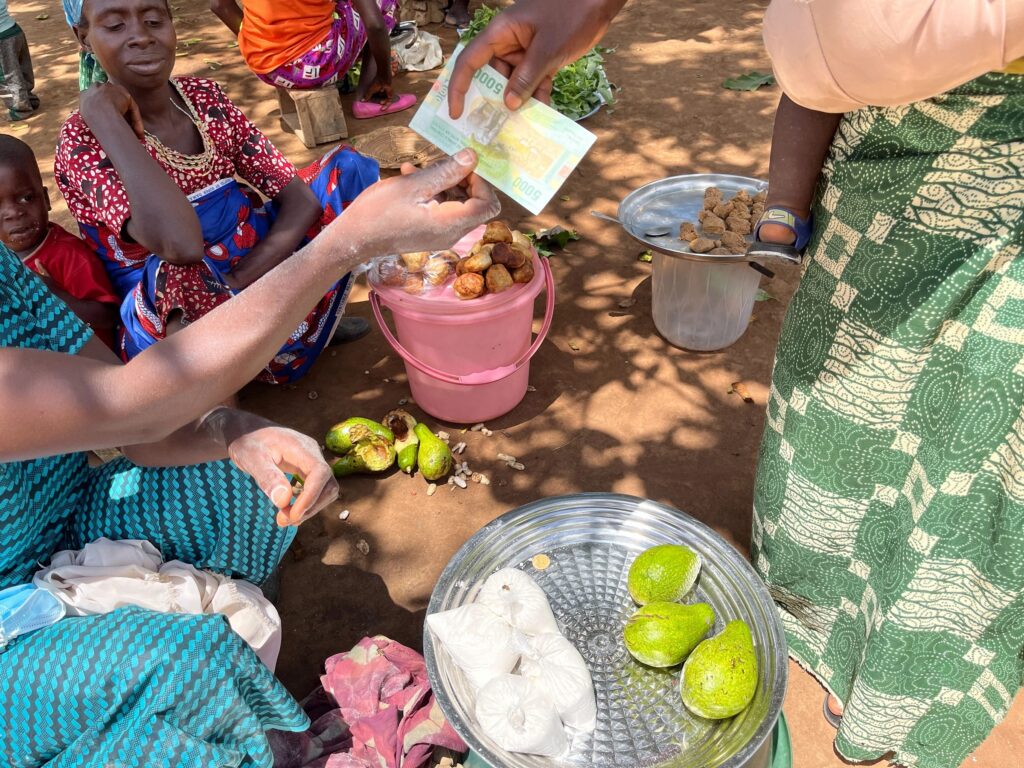 Kvinne betaler for tre avokadoer på et marked i Den sentralafrikanske republikk.