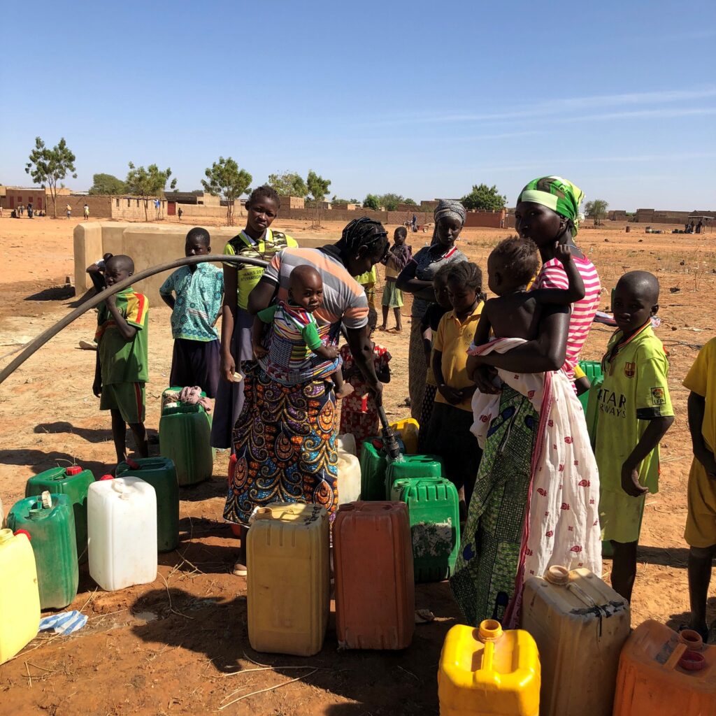 Kvinner og barn samlet ved en vannpumpe i Mali.