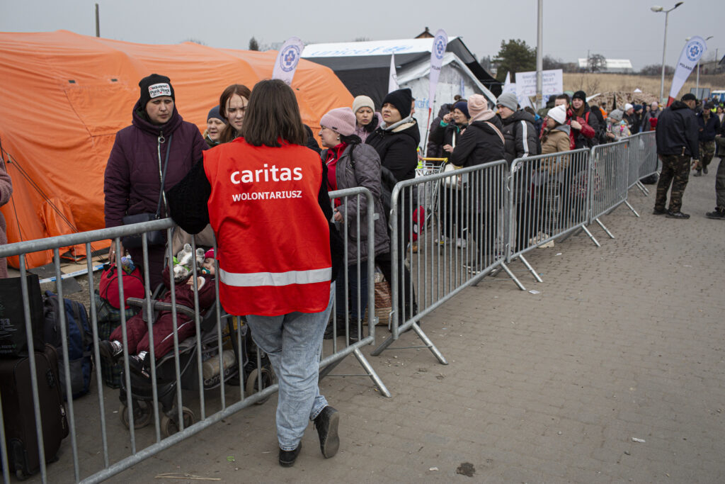 Hjelpearbeider fra Caritas tar i mot ukrainske flyktninger på grensen til Polen