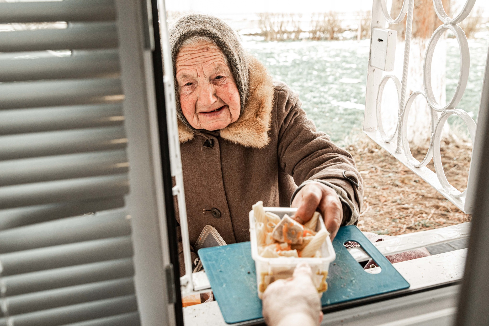 Elderly Ukrainian woman is handed a hot meal