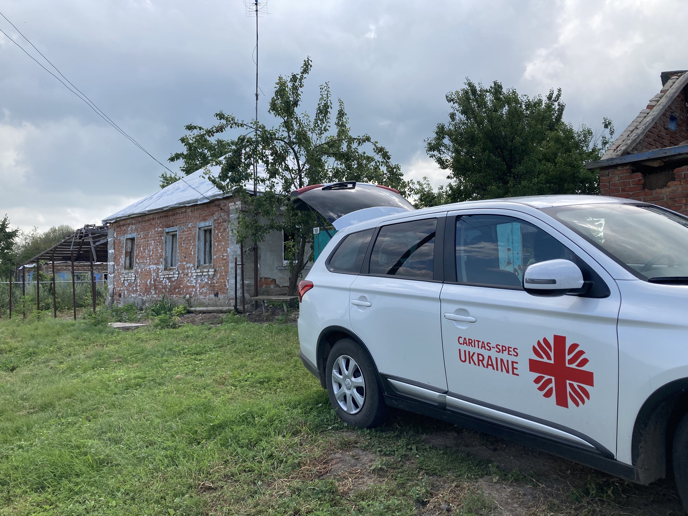 The car of Caritas Spes is parked outside a house in one of the villages outside Kharkiv