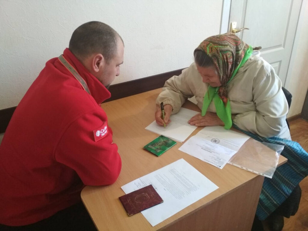 En eldre dame i Kharkiv fyller ut skjema for kontantstøtte