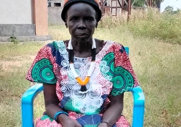A woman from South Sudan in a colorful dress - sitting in a chair
