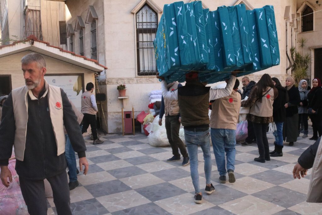 Caritas-personell bærer madrasser til jordskjelvsofre i Syria