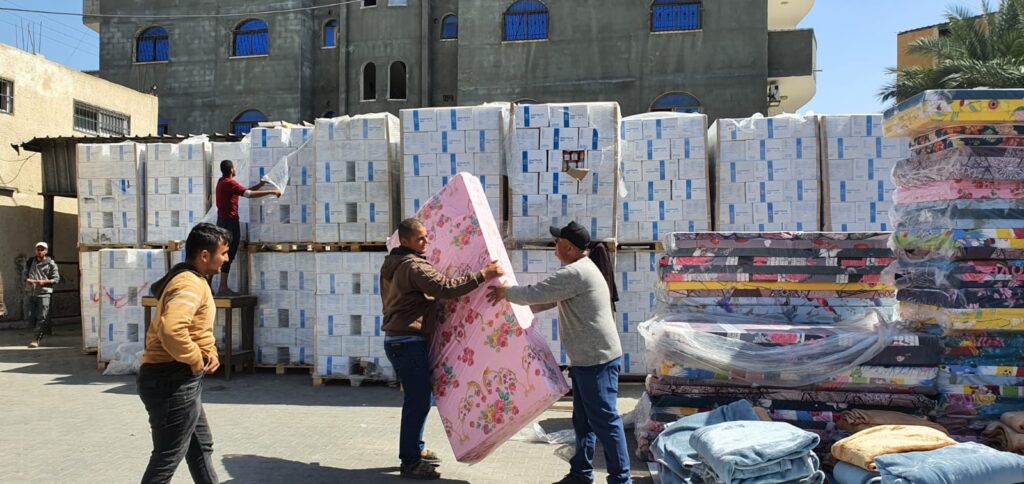 Gaza: Frivillige hjelpearbeidere i Caritas deler ut madrasser og esker med mat til sivilbefolkningen