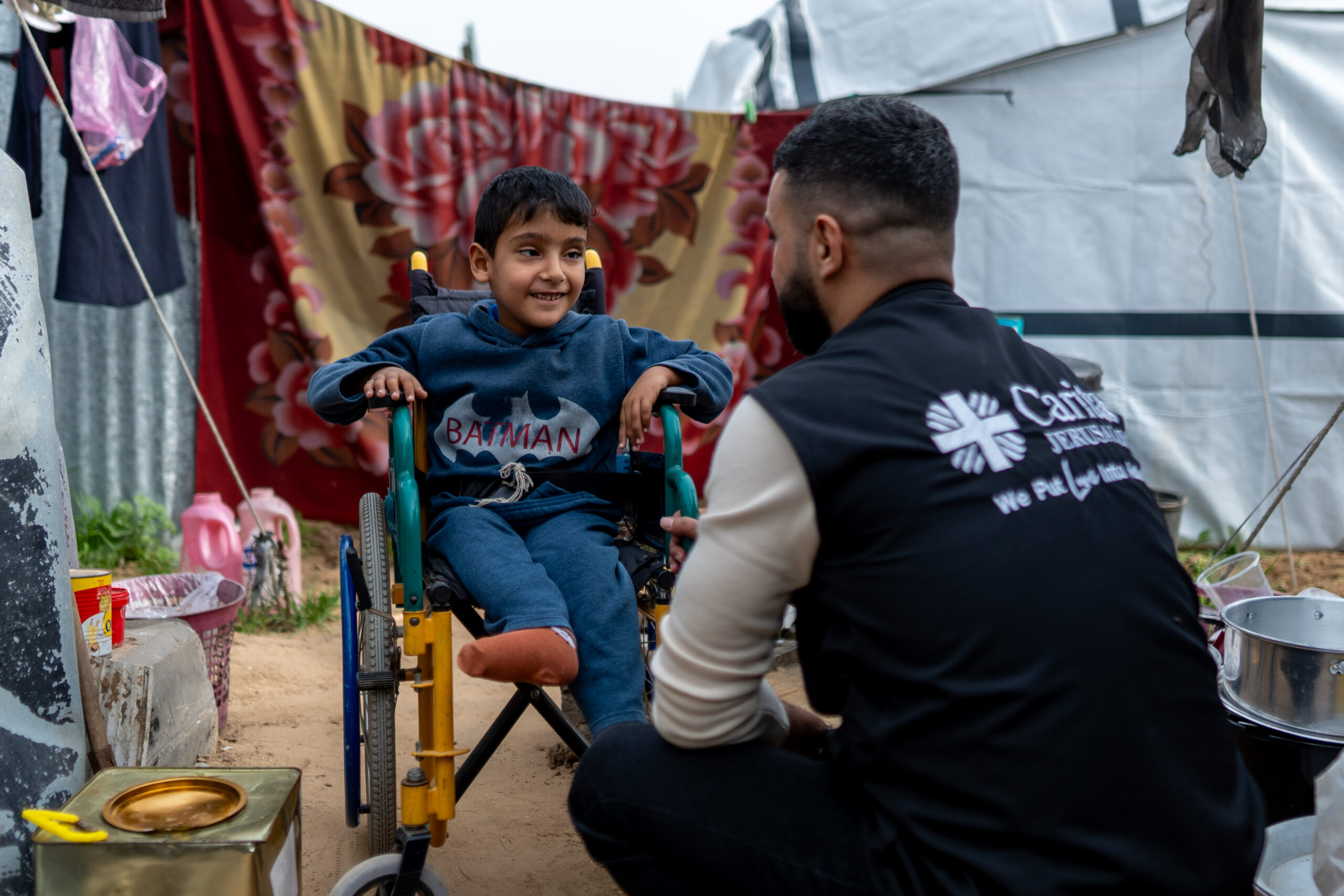 These images tell the story of Mahmoud Ibrahim Lubbad and his son Obaida, 8, displaced to Safi Camp in Gaza. Obaida lives with spina bifida, hydrocephalus, and partial paralysis — conditions that demand constant medical care, physiotherapy, and specialized nutrition. None of which are available in a tent.