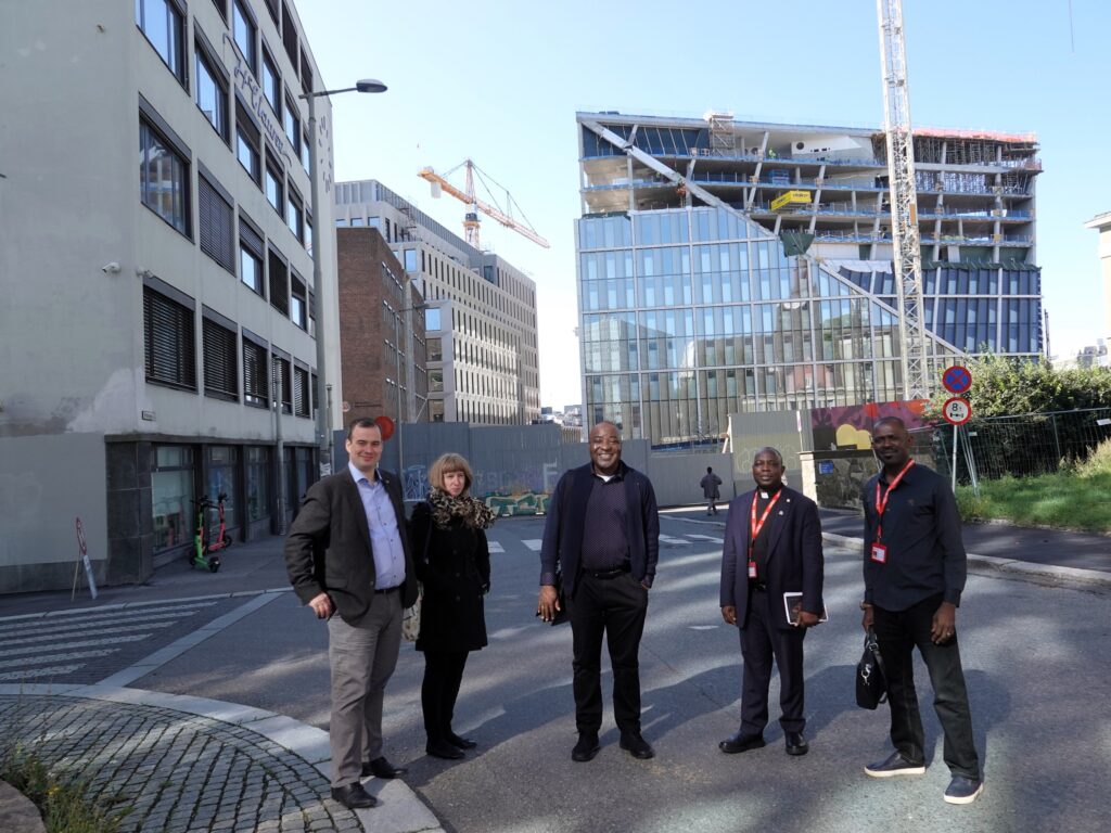 Alexander Golding og Tale Hungnes i Caritas Norge står sammen med tre representanter fra Caritas Nigeria med regjeringskvartalet i bakgrunnen