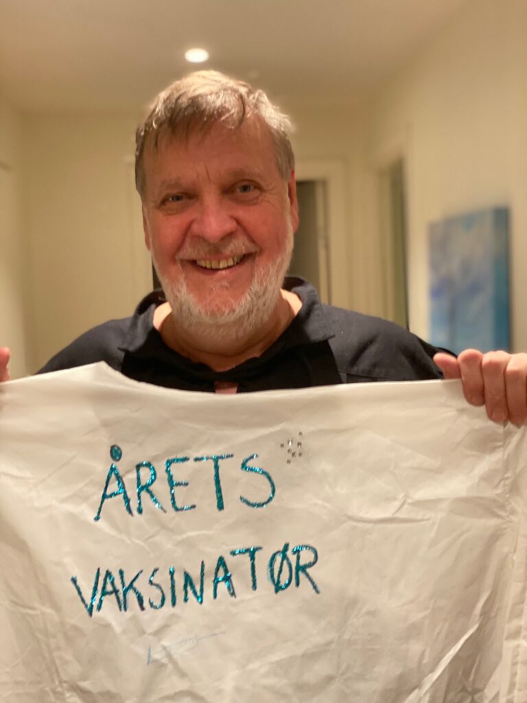 Peter Kuran holder frem t-skjorte med teksten Årets vaksinatør