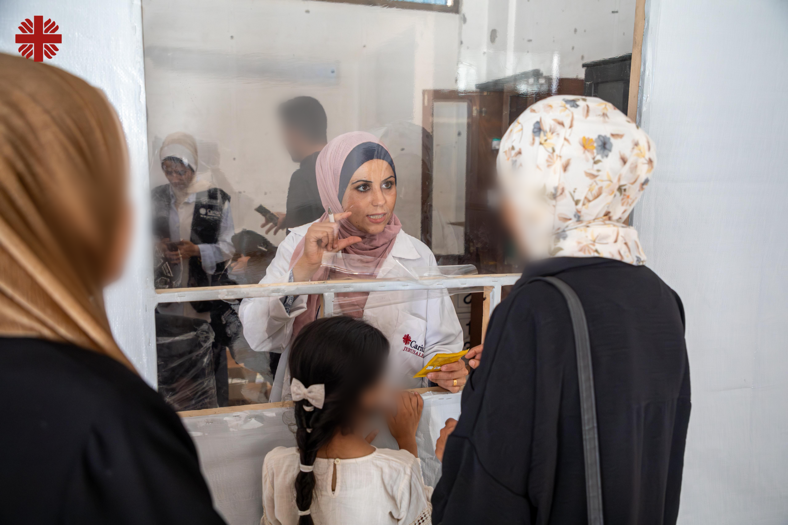 Kvinnelig ansatt ved Caritas Jerusalems helseklinikk i Gaza svarer på spørsmål fra pasienter.