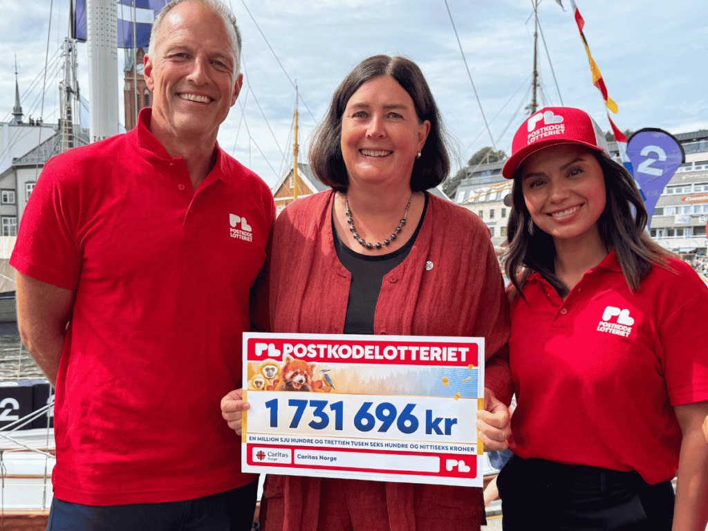Generalsekretær Ingrid Rosendorf Joys i Caritas Norge holder en sjekk fra Postkodelotteriet, og står sammen med Postkodelotteriets ambassadører er Jorun Stiansen og Tom Stiansen.