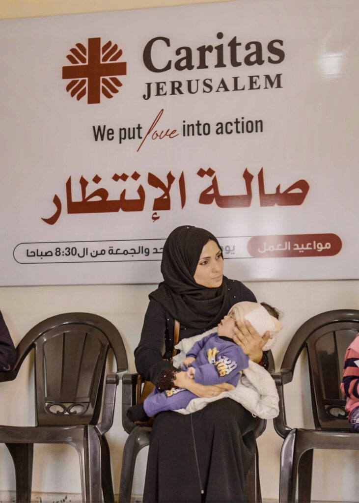 Salami Mohammad Saad holder sønnen i armene på venterommet inne på klinikken til Caritas i Gaza.