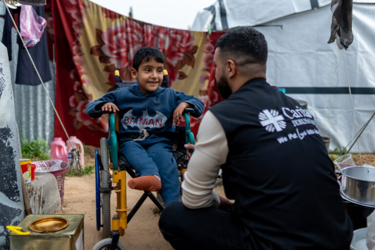 These images tell the story of Mahmoud Ibrahim Lubbad and his son Obaida, 8, displaced to Safi Camp in Gaza. Obaida lives with spina bifida, hydrocephalus, and partial paralysis — conditions that demand constant medical care, physiotherapy, and specialized nutrition. None of which are available in a tent.