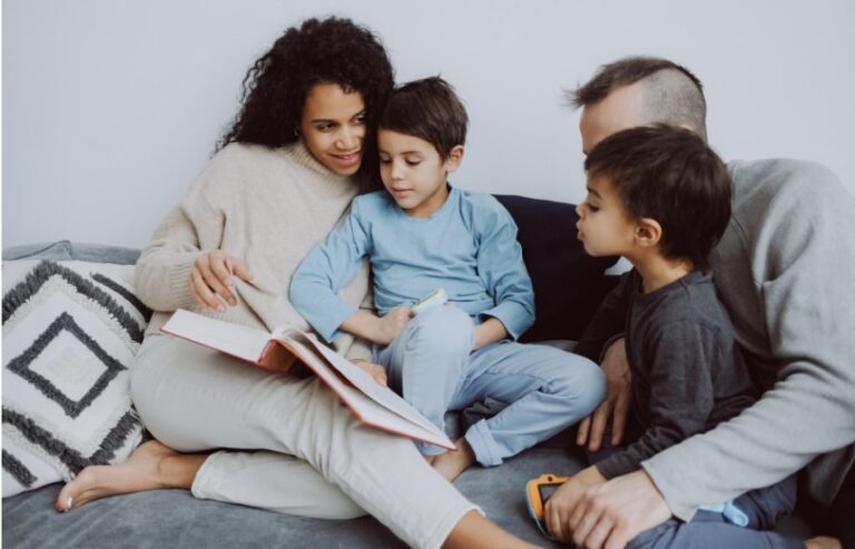 Familie; mor, far og to sønner samlet i sofaen omkring en bok.