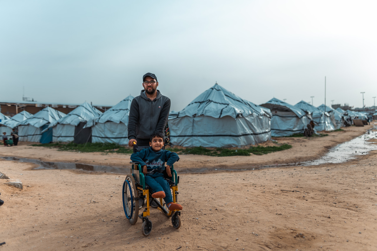 Obaida er åtte år gammel og lever med ryggmargsbrokk i en flyktningleir i Gaza. Bak rullestolen står faren hans. (Foto: Raw Media/Trocaire)